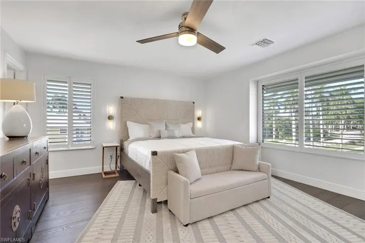 Bedroom featuring a ceiling fan, multiple windows, and dark wood finished floors