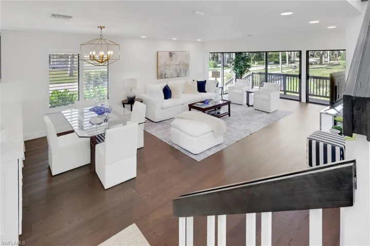 Living room with dark wood finished floors, a chandelier, and recessed lighting