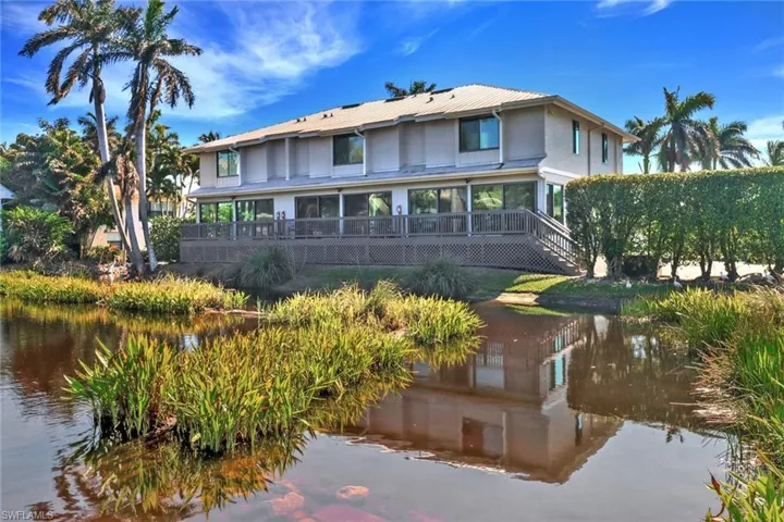 Back of house with a metal roof, stairs, a deck with water view, and stucco siding
