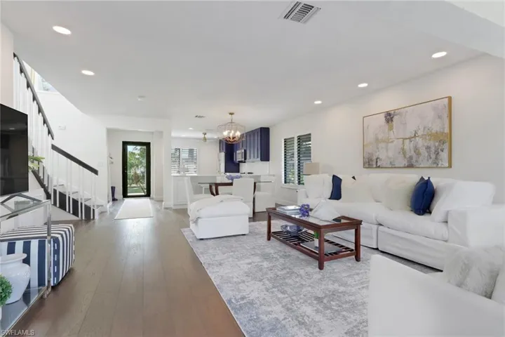 Living room with a chandelier, wood-type flooring, recessed lighting, and stairs
