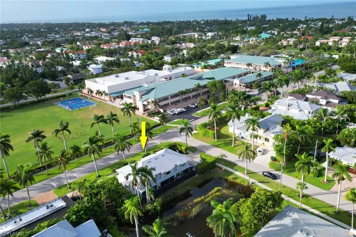 Aerial view of property and surrounding area featuring a nearby body of water and nearby suburban area