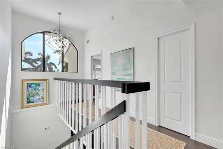 Hallway featuring an upstairs landing and dark wood finished floors