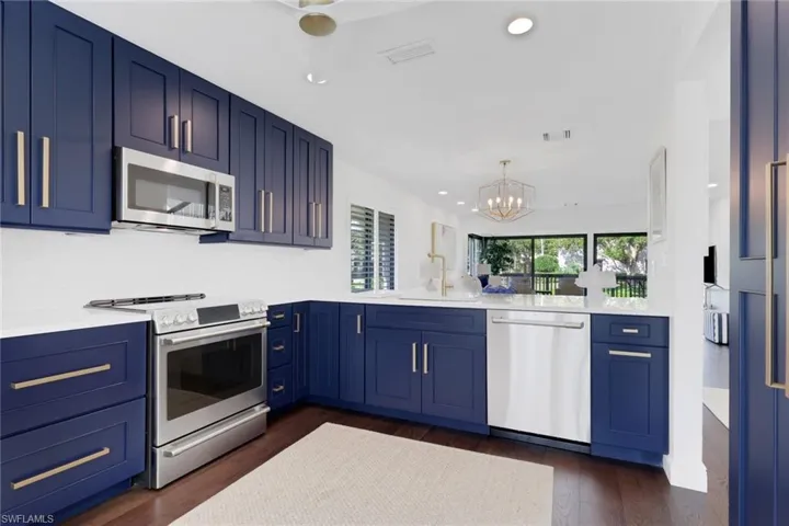 Kitchen with blue cabinetry, stainless steel appliances, a chandelier, and recessed lighting