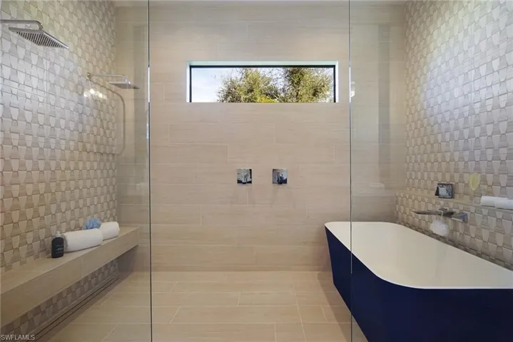 Full bath featuring tile walls, a soaking tub, and a walk in shower