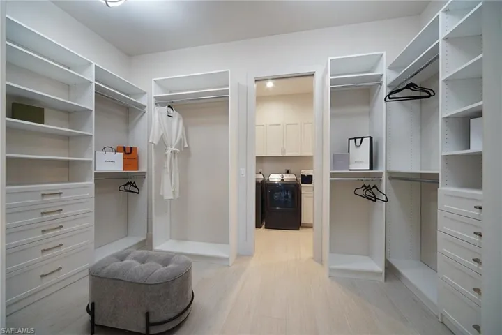 Walk in closet with light wood-type flooring and independent washer and dryer