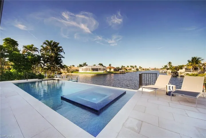 View of pool with a water view, a patio, and a pool with connected hot tub