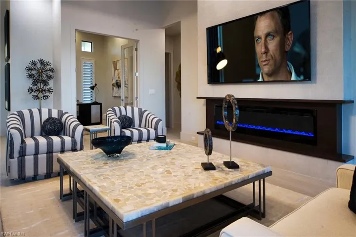 Living area featuring a glass covered fireplace and baseboards
