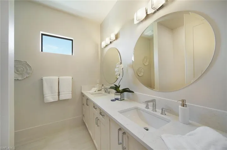 Full bathroom with double vanity and baseboards