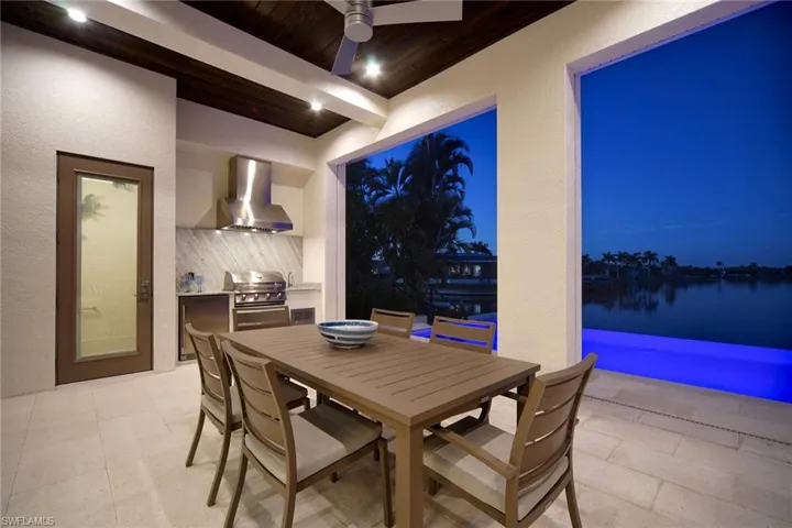 View of patio featuring outdoor dining space, an outdoor kitchen, a ceiling fan, and a water view