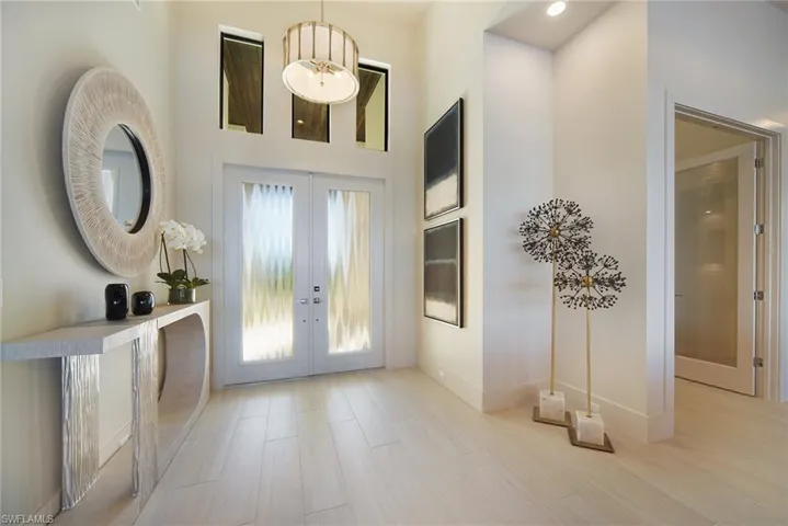 Foyer with french doors, light wood finished floors, and a high ceiling