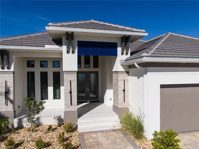 Property entrance with stone siding, a tile roof, stucco siding, french doors, and a garage