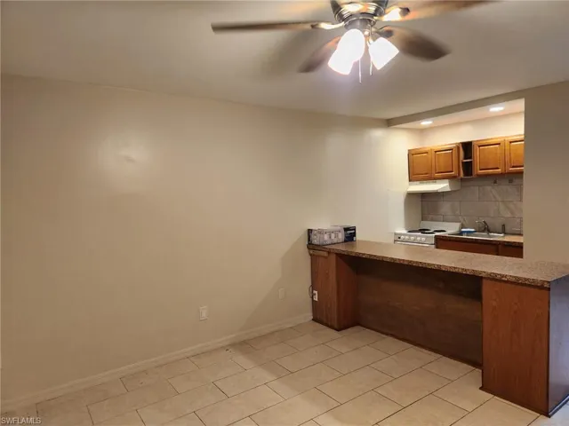 Kitchen featuring dark countertops, a peninsula, decorative backsplash, white electric range oven, and ceiling fan