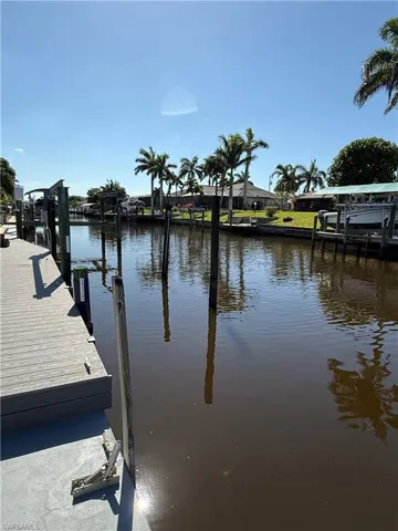 Canal-front property featuring a private dock, mature palm trees, and waterfront access