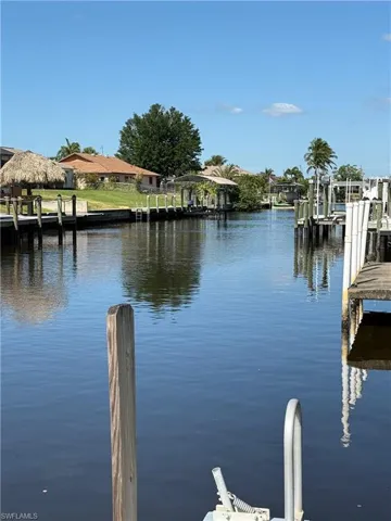 Waterfront property featuring multiple boat docks, a covered boat lift, and a thatched tiki hut