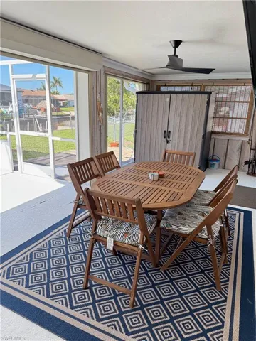 Screened enclosure with sliding glass doors, a ceiling fan, and a built-in storage cabinet