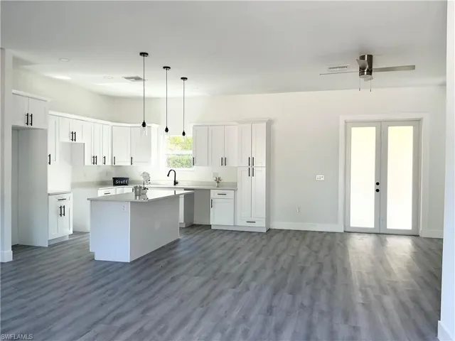 Kitchen featuring white cabinetry, decorative light fixtures, french doors, a kitchen island, and dark wood-style flooring