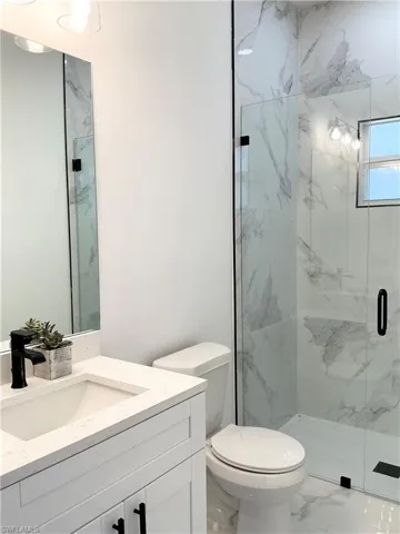Bathroom with a marble finish shower, vanity, and marble look tiles