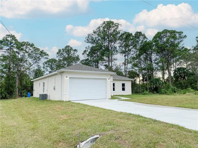 View of property exterior with stucco siding, concrete driveway, and a yard