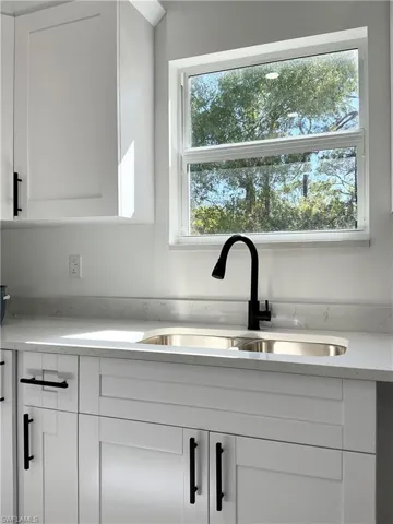 Kitchen view of white cabinetry and light stone countertops
