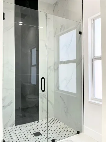 Full bath with a marble finish shower and baseboards
