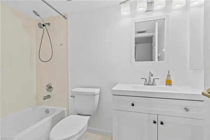 Full bathroom with vanity, tile patterned flooring, tiled shower / bath combo, and toilet