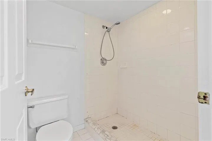 Bathroom with tile patterned floors, tiled shower, and toilet