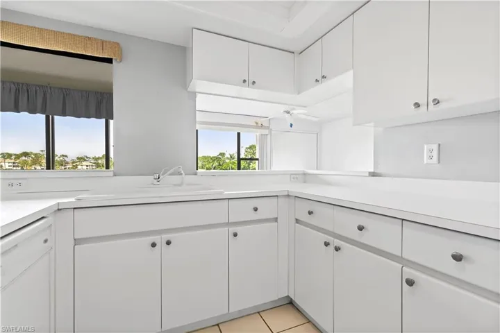 Kitchen with white cabinets, white dishwasher, sink, and light tile patterned floors