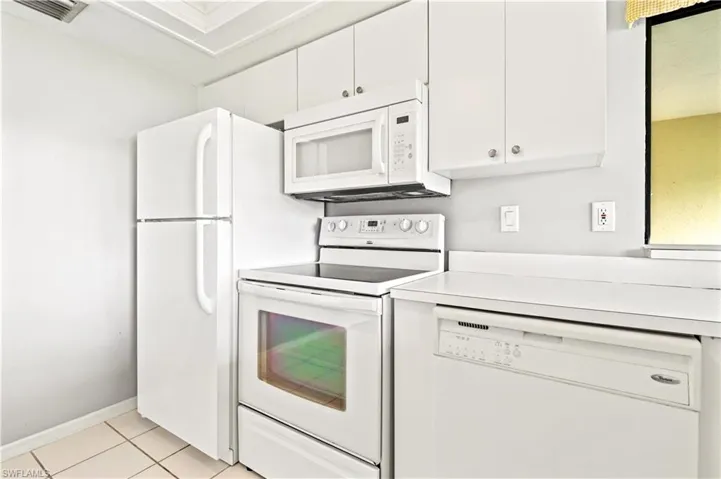 Kitchen featuring white cabinetry, white appliances, and light tile patterned floors
