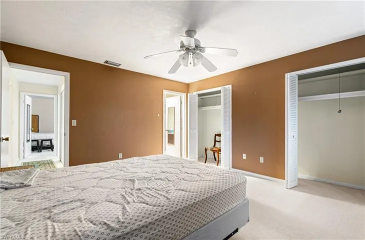 Bedroom with multiple closets, carpet flooring, and ceiling fan