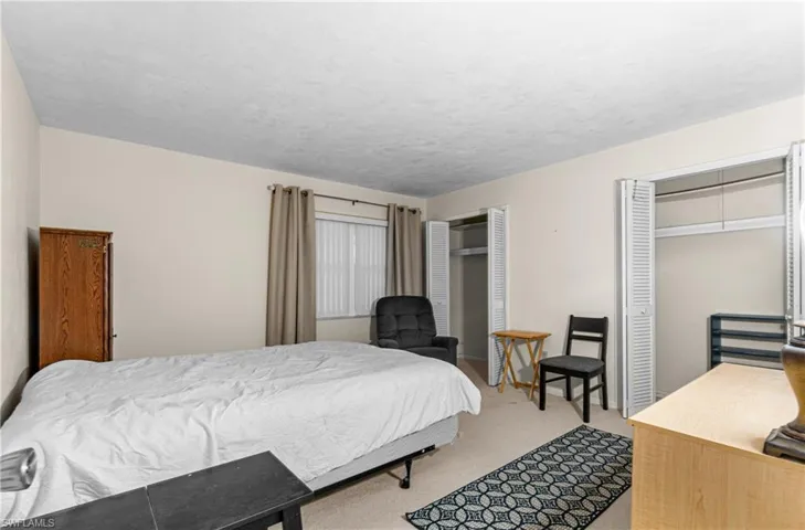 Bedroom featuring multiple closets and light colored carpet