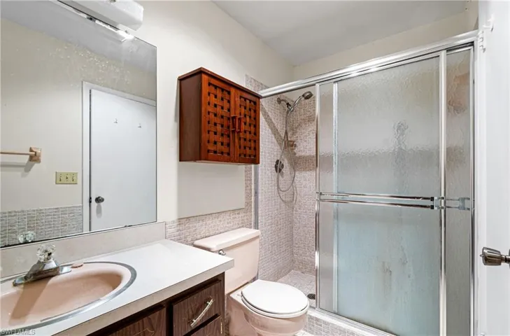Full bath with vanity, a stall shower, and tile walls