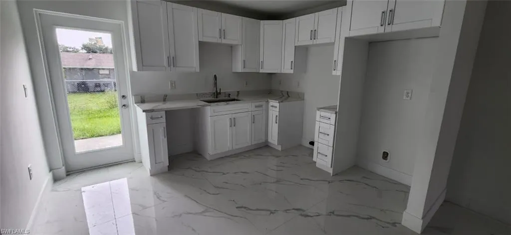 Kitchen featuring light marble finish floors and white cabinetry