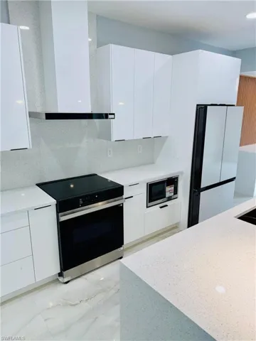 Kitchen featuring white cabinetry, black electric range, wall chimney range hood, and modern cabinets