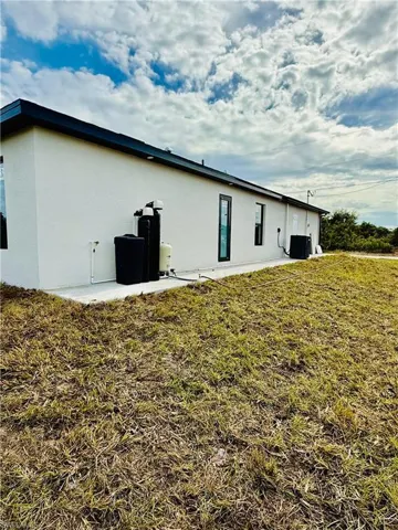 View of side of property with a patio area, stucco siding, and a yard