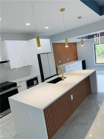 Kitchen with light marble finish flooring, electric range oven, white cabinets, and recessed lighting