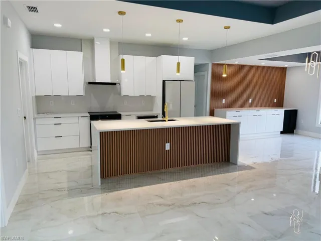 Kitchen with modern cabinets, a center island with sink, white cabinetry, and recessed lighting