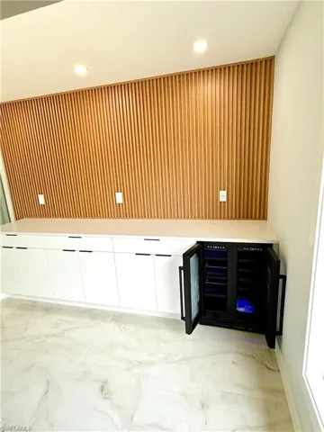 Misc room featuring recessed lighting, wine cooler, and light marble finish floors