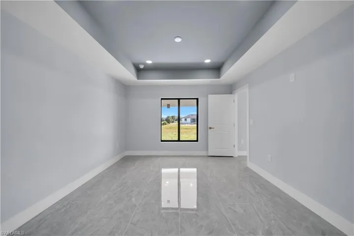 Spare room featuring light marble finish floors, a raised ceiling, and recessed lighting