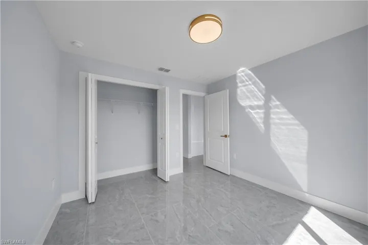 Unfurnished bedroom featuring a closet and light marble finish flooring