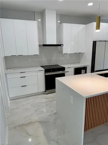 Kitchen with modern cabinets, black range with electric cooktop, wall chimney exhaust hood, white cabinetry, and recessed lighting