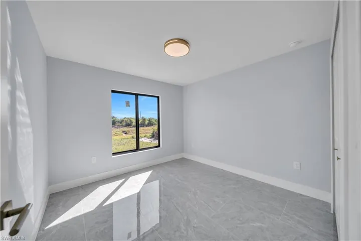 Spare room with light marble finish flooring and baseboards