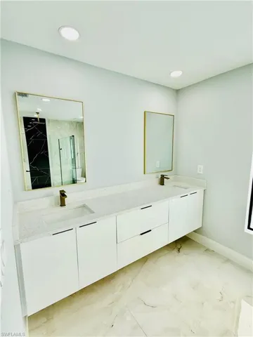 Bathroom featuring double vanity, a marble finish shower, recessed lighting, and light marble finish flooring