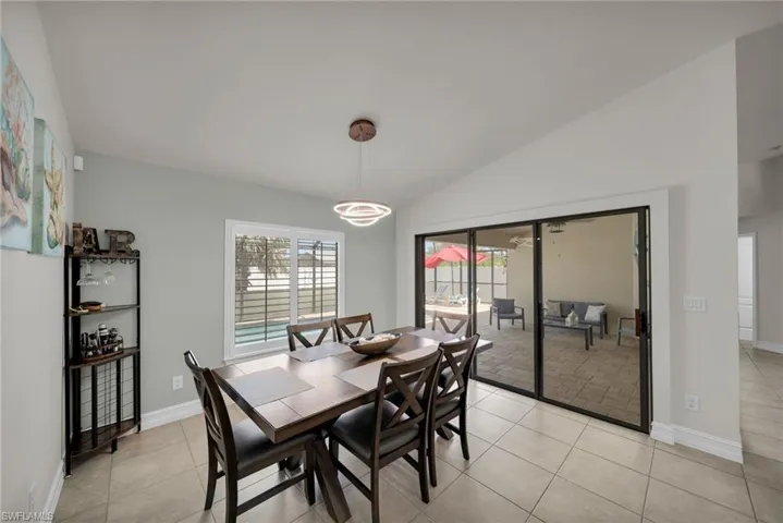 Dining room featuring baseboards, light tile patterned floors, and lofted ceiling