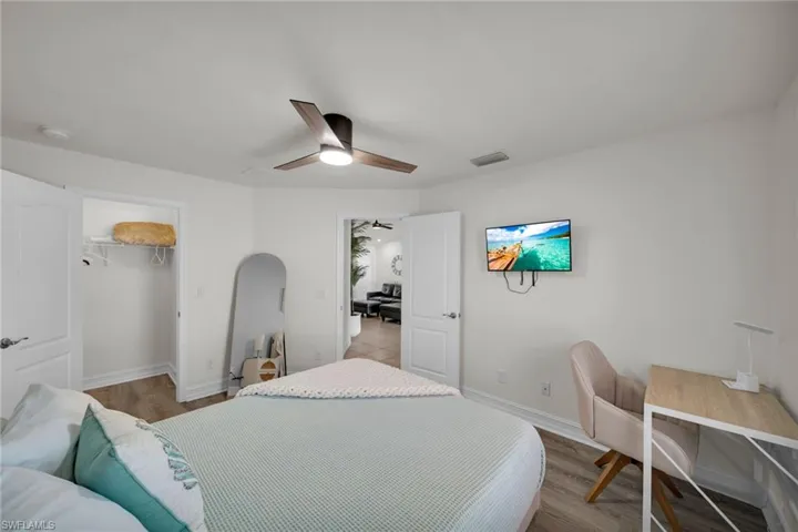 Bedroom featuring a spacious closet, wood finished floors, baseboards, visible vents, and a ceiling fan