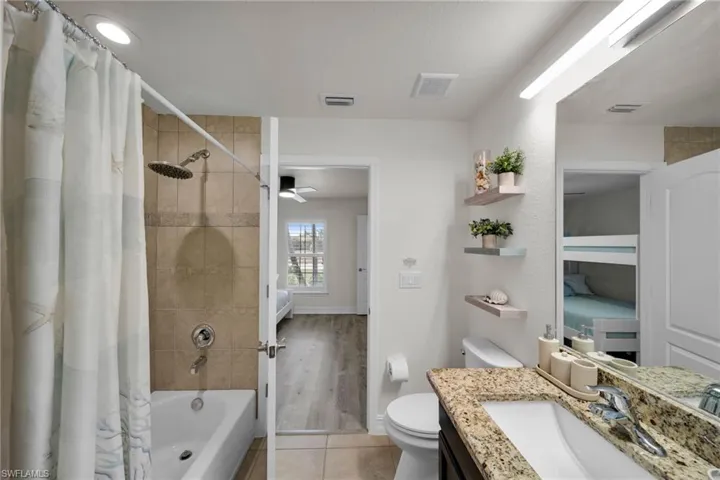 Full bathroom with shower / tub combo, visible vents, toilet, tile patterned floors, and vanity