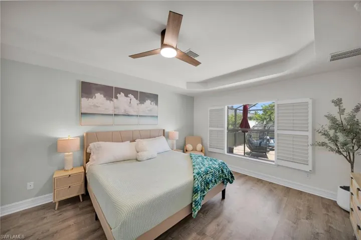 Bedroom featuring visible vents, a raised ceiling, and baseboards