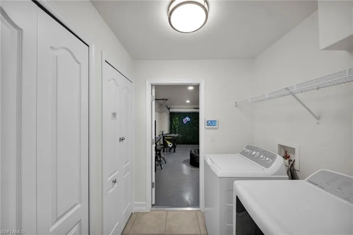 Clothes washing area with washing machine and dryer, laundry area, and baseboards