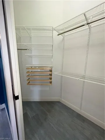 His custom Elfa walk in closet. Tile floor that looks like gray hardwood.