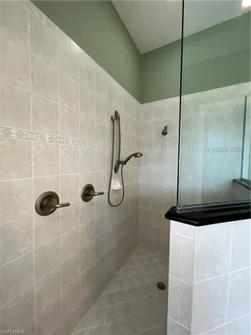 Large Walk In Shower has double shower heads & a bench & is finished off with black Quartz.