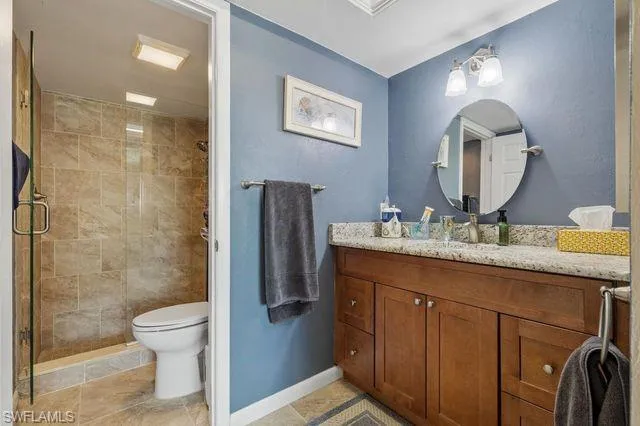 Bathroom with tile flooring, vanity, toilet, and a shower with door
